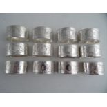 A SET OF TWELVE SILVERPLATED FLAT BOTTOM NAPKIN RINGS. Bright cut shell and flower heads and each