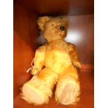 A vintage straw-filled teddy bear with r
