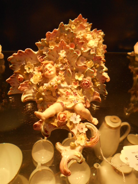 A pair of continental porcelain wall sconces decorated with encrusted flowers and leaping children