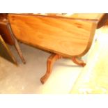 A Victorian mahogany cross-banded drop leaf breakfast table resting on a turned pedestal base on