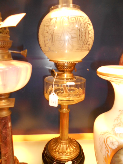 A Victorian 'Express' ornate glass and brass oil lamp resting on painted terracotta base