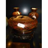 A pair of cloisonne vases and a bowl resting on carved wooden bases