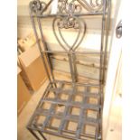 A pair of scrolling iron garden chairs with heart shaped backs