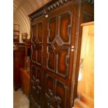 A Jacobean style oak wardrobe with dentil cornice above a pair of geometric applied moulded doors