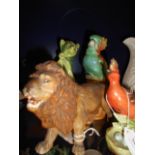 A 19th C ceramic model of a lion with glass eyes, a green glazed seated cat with bandages to head,