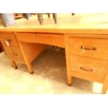 A mid 20th C light oak desk the top with slides over a central frieze drawer with Ivorine table