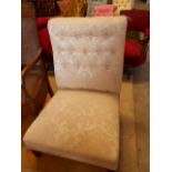 A button-back easy chair in cream damask upholstery