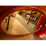 An early 20th C oval mahogany framed wall mirror with bevel edged plate
