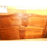 A mid 20th C oak serpentine shaped 4ft 6" double bed the panelled head and foot boards carved with