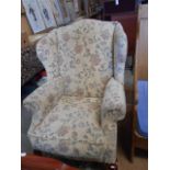 A late 20th C hump and wing back armchair with scrolled arms raised on squat cabriole supports