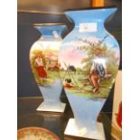 A pair of early 20th C blue ground vases of shaped form decorated with gypsies in rural scene