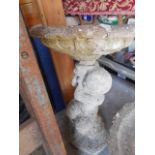 A reconstituted stone figural bird bath