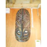 An African carved hardwood polychrome tribal mask with bird carving to nose