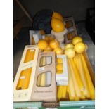 A box of assorted yellow candles and candle holders