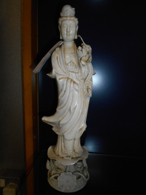 A blanc de chine porcelain figure or an Oriental female raised on a floral encrusted base