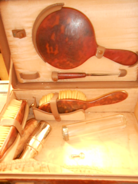 An early 20th C leather vanity case fitted with tortoise shell brushes and mirror and a silver