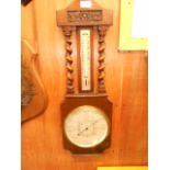 A 1930's oak cased barometer and thermometer surmounted with a floral carved panel over barley