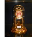 A brass 100 hour clock the red dial with Arabic numerals raised on column supports and circular