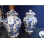A pair of 19th C Delft blue and white lidded vases with floral decoration,