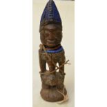 18th/19thC carved wood tribal figure with blue bead necklace,