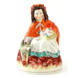 Property of a lady - a Victorian Staffordshire figure of Red Riding Hood, modelled seated with a