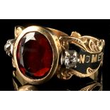 A Victorian 18ct gold & black enamel mourning ring set with a central oval cut garnet flanked by two