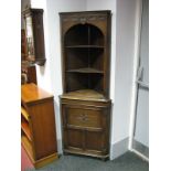 An Oak Free Standing Corner Unit, the cornice with a frieze of carved foliate lunettes, canted