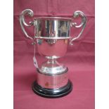 A Hallmarked Silver Twin Handled Trophy Cup, marks rubbed, of plain circular form, between twin leaf