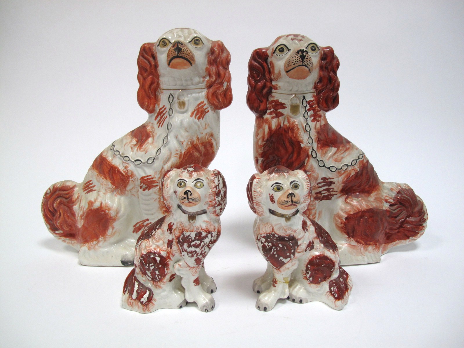 A Pair of XIX Century Staffordshire Spaniel Dogs, with rust red patches and black feet, 30.5cms