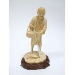 A Late XIX Century Japanese One Piece Carved Ivory Okimono, as a farmer, standing with a hoe,