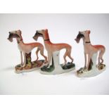 A Pair of XIX Century Staffordshire Pottery Greyhound Dogs, each holding game, on naturalistic base,