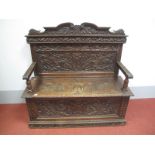 A Late XIX Century Oak Box Settle, the panel back carved with 'C' scrolls and central shield with