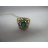 An Emerald and Diamond Cluster Ring, the central oval emerald claw set, within border of brilliant