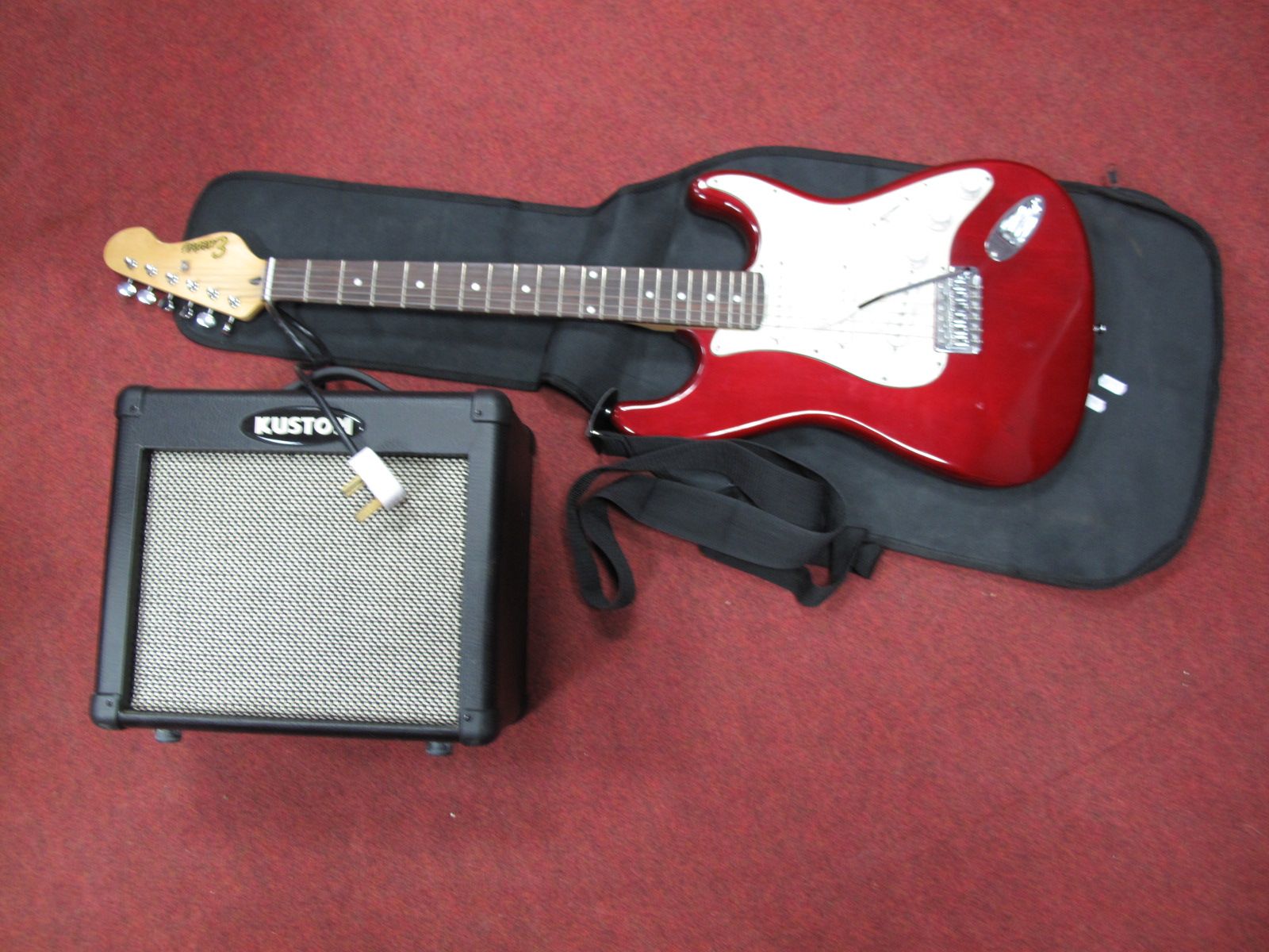 A Stratocaster Style Encore Electric Guitar, with rouge body, together with a "Kustom" amplifier.