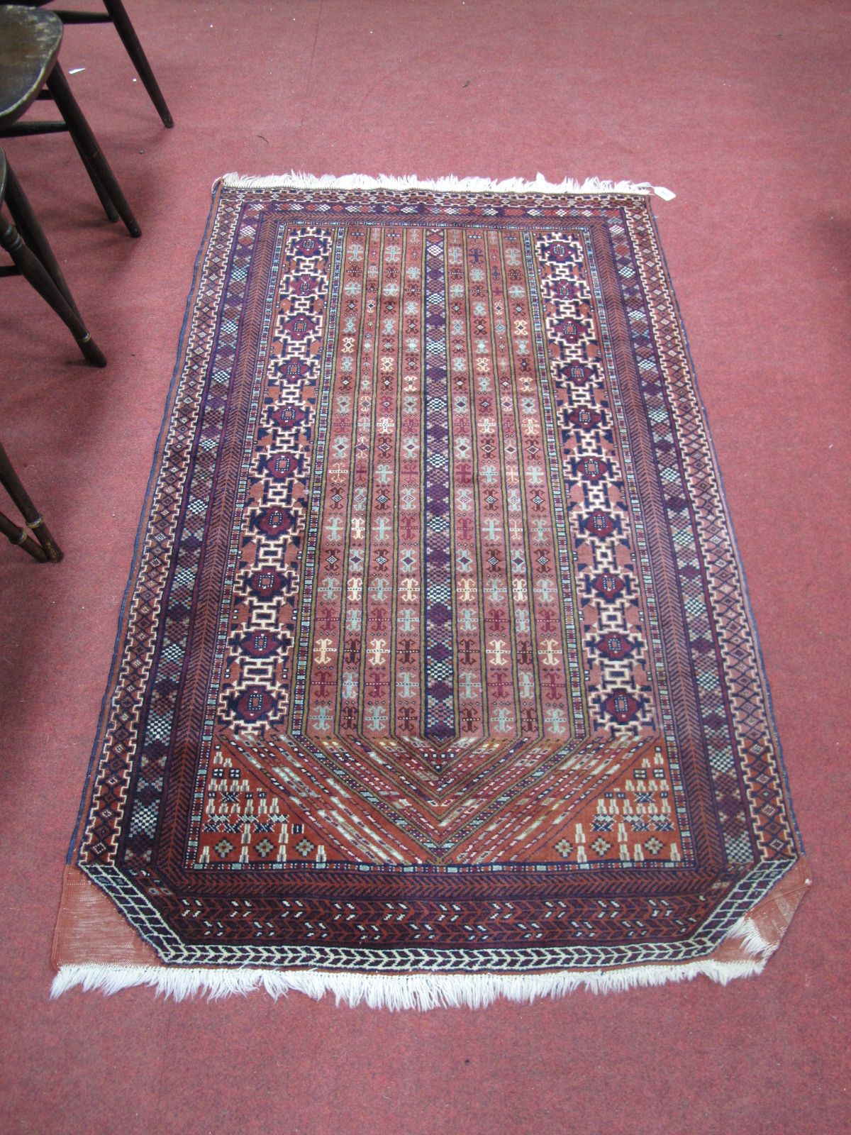 A Middle Eastern Tasseled Rug, centrally decorated with stylized geometric rows within multi
