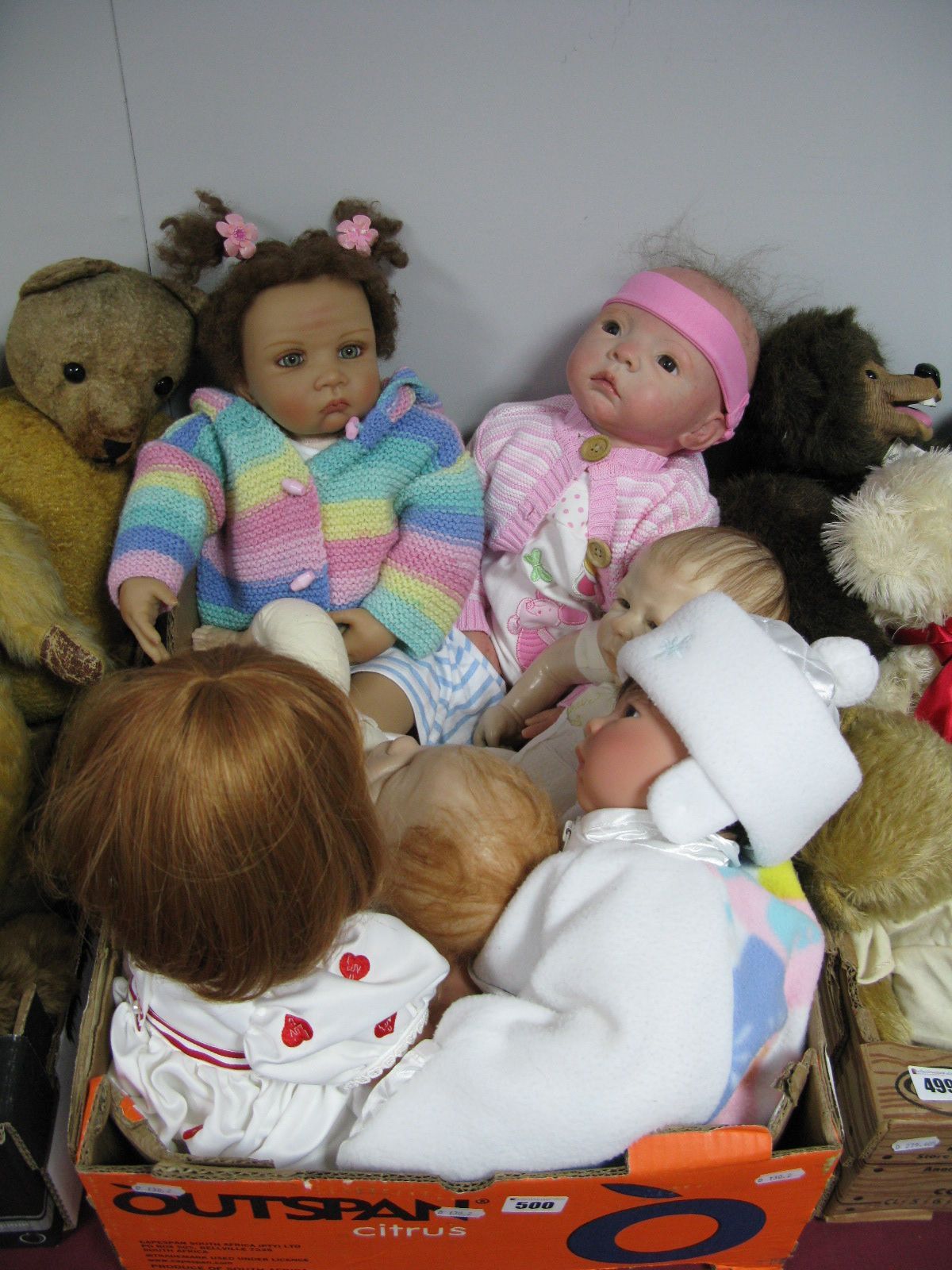 A Reborn Doll, wearing pink cardigan, together with other dolls including Ashton Drake dolls, Anna