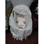 A Reborn Doll, wearing white knitted jumper in a moses basket, together with another basket.