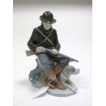 A Royal Copenhagen Porcelain Group, modelled as a young hunter, seated with shotgun, a recumbent