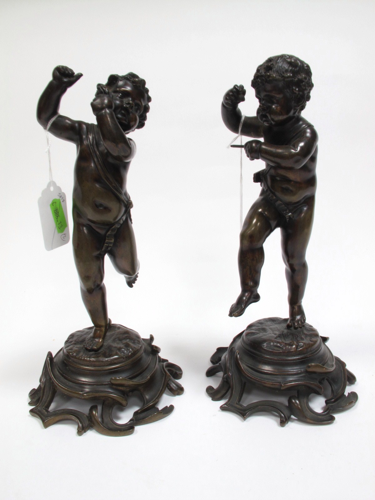 A Pair of XX Century Cast Bronze Figures of Putti, one playing a triangle, the other a flute (both