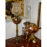 An antique copper oil lamp, with frilly glass light shade above copper reservoir, raised on ornate