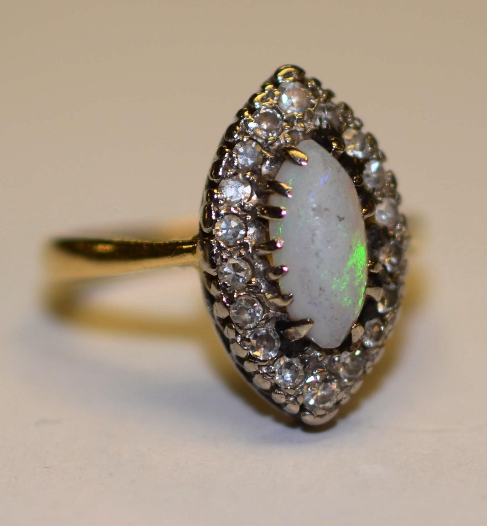 An 18ct gold and platinum opal and diamond dress ring, the central opal surmounted by 18 round cut