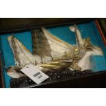 A Chinese export white metal model of a junk decorated with masts and figures on deck, raised on