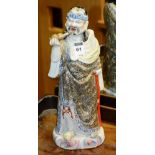 A Japanese porcelain figure, depicting an older man holding a vessel in right hand and orange glazed