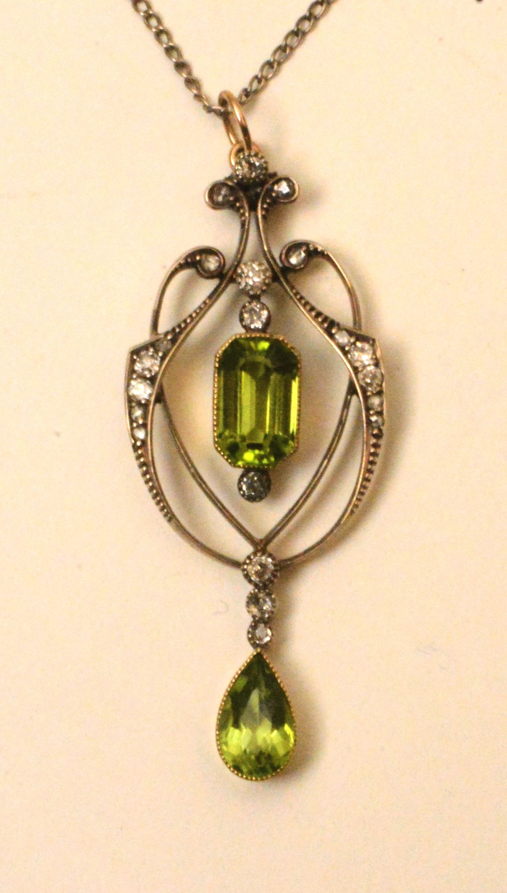 A yellow metal peridot and diamond pendant, the central emerald cut peridot drop (approx. 1.5ct)