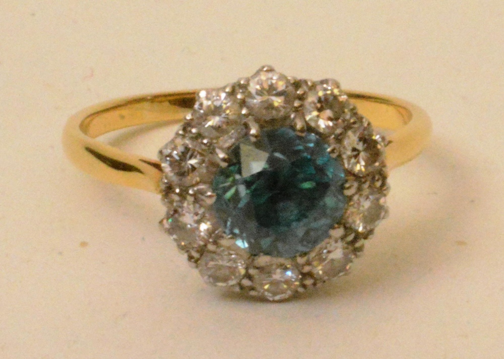 A yellow metal blue zircon and diamond flowerhead ring, the central blue topaz surrounded by 10