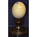 An ostrich egg, raised on turned mahogany stand with circular foot,