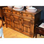 A Jacobean style oak dresser base, with three short drawers above three carved panelled doors,