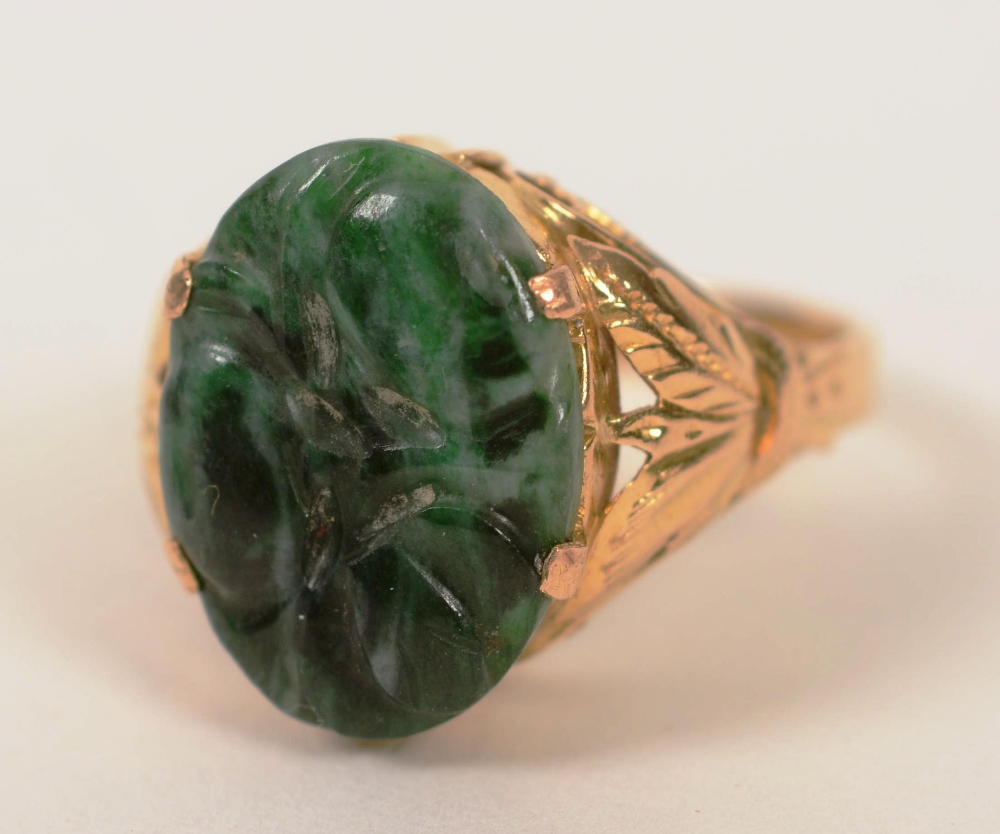 A 22ct gold Oriental jade ring, with lotus flower carved to jade and foliate gold decoration to