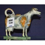 A 19th century Staffordshire cow creamer and cover, with orange and black sponged decoration to body