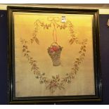 An 18th century framed embroidered panel, depicting a hanging basket within a floral wreath,